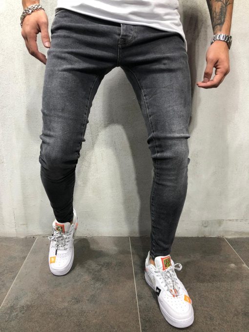 Voorzijde grijze denim heren jeans met skinny pasvorm, gemaakt van stretch stof. Gecombineerd met wit T-shirt en witte sneakers.