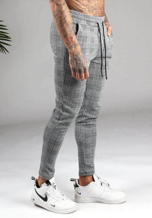 Zijaanzicht heren chino broek grijs met kleine wit-zwarte ruit, skinny fit, twee broekzakken en elastische taille met trekkoord.
