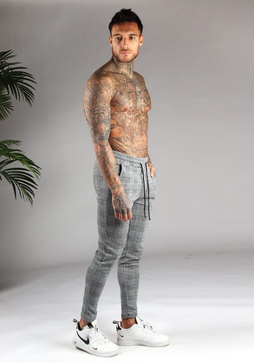 Zijkant heren chino broek grijs met kleine wit-zwarte ruit, skinny fit, twee broekzakken en elastische taille met trekkoord.