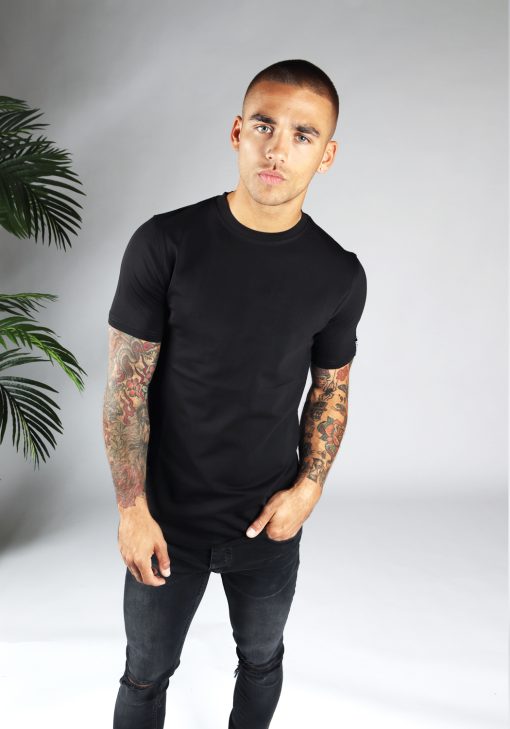 Vooraanzicht heren T-shirt in zwarte kleur en een straight fit pasvorm. Het model draagt een donkere jeans en heeft zijn linkerarm in zijn linker broekzak.