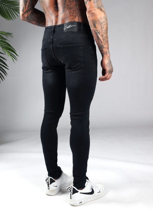 Achterkant zwarte heren skinny jeans. Gemaakt van stretch stof en voorzien van vier zakken, knoopsluiting en riemlussen.