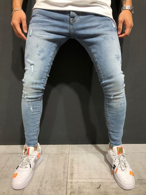 Voorkant lichtblauwe denim skinny jeans voor heren met damaged afwerking. Gecombineerd met wit T-shirt en witte sneakers.