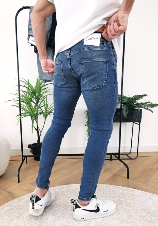Achterkant denim heren skinny jeans van stretch stof en voorzien van broekzakken, knoopsluiting en riemlussen.
