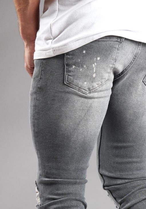 Close up achterzak lichtgrijze denim heren skinny jeans met damaged look, scheuren en verfspatten.