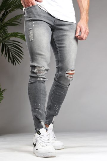 Voorkant lichtgrijze denim heren skinny jeans met damaged look, scheuren en verfspatten. Gecombineerd met wit T-shirt en witte sneakers.