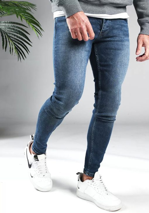 Rechter zijaanzicht blauwe heren skinny jeans met twee broekzakken, twee kontzakken, knoopsluiting en riemlussen. Gecombineerd met grijze sweater en witte sneakers.