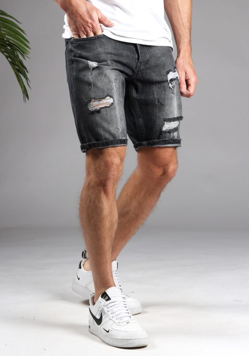Vooraanzicht van model gekleed in donkergrijze shorts met damaged details. Het model heeft een hand in zijn broekzak en draagt een wit shirt.