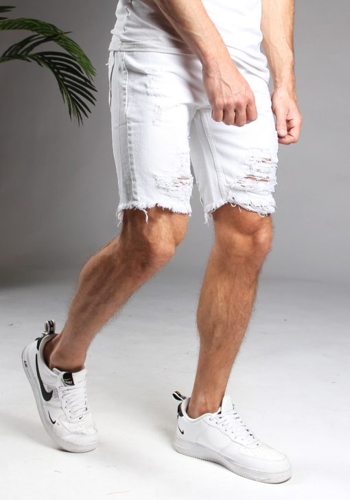 Rechter zijaanzicht witte heren shorts met scheuren, gemaakt van stretch stof. Voorzien van broekzakken, een knoopsluiting en riemlussen. Gecombineerd met wit T-shirt en witte sneakers.