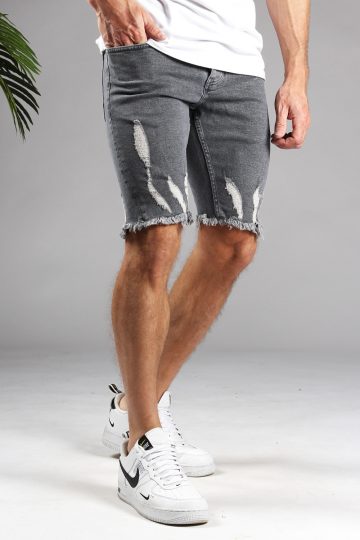 Schuin vooraanzicht van model gekleed in grijze shorts met damaged details. Het model heeft een hand in zijn zak en draagt een wit shirt.