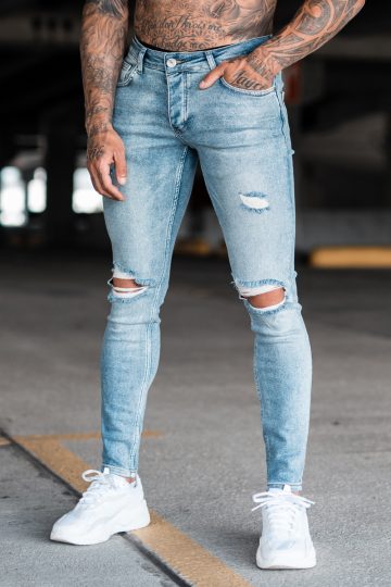 Voorzijde denim heren skinny jeans met scheuren. Gemaakt van stretch stof en voorzien van vier zakken, knoopsluiting en riemlussen.