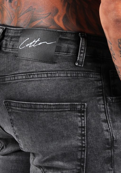 Close up van zwart label aan de achterkant van zwarte jean shorts. Op het logo staat het witte signature Cotton District logo.