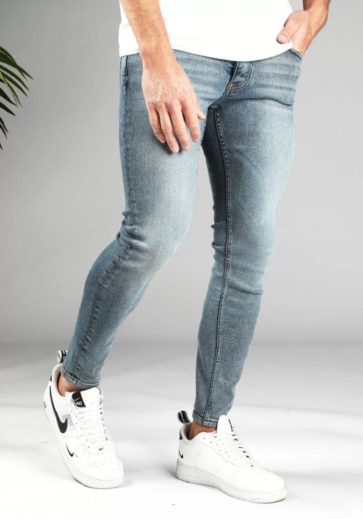 Voorkant licht blauwe denim light wash heren skinny jeans, gemaakt van stretch stof. Voorzien van vier zakken, knoopsluiting en riemlussen. Gecombineerd met wit T-shirt en witte sneakers.