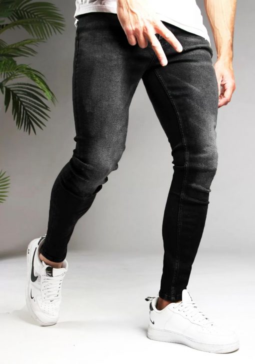 Voorkant zwarte heren skinny jeans met lichte vegen. Gemaakt van stretch stof en voorzien van vier zakken, knoopsluiting en riemlussen. Gecombineerd met witte sneakers en een wit T-shirt.