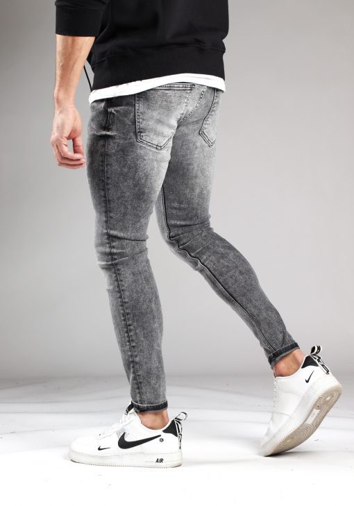 Achterkant grijze heren skinny jeans met broekzakken, knoopsluiting en riemlussen. Gecombineerd met zwarte hoodie en witte sneakers.