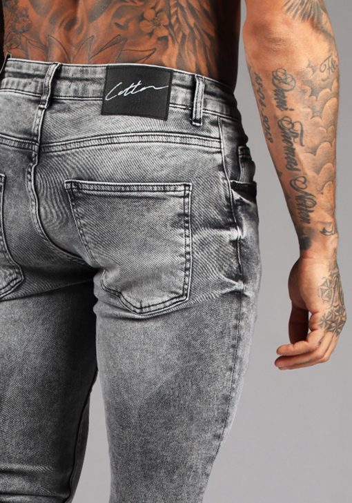 Close up achterkant grijze heren skinny jeans met broekzakken, knoopsluiting en riemlussen.