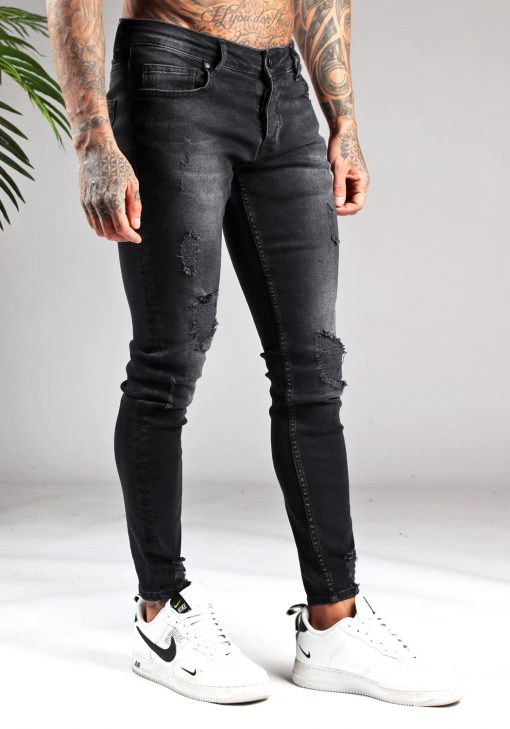Rechter zijaanzicht zwarte heren jeans met skinny pasvorm en lichte damaged uitstraling, voorzien van vier zakken, knoopsluiting en riemlussen.