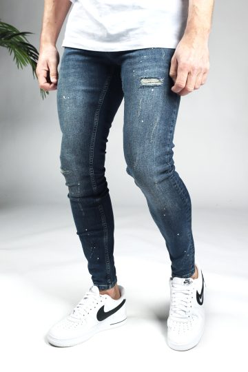 Linker zijkant blauwe damaged denim heren skinny jeans met verfspetters.