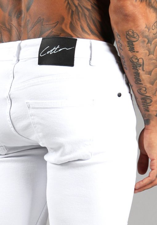 Close up van de achterkant van witte jean shorts en het zwarte label met daarop het witte signature Cotton District logo.