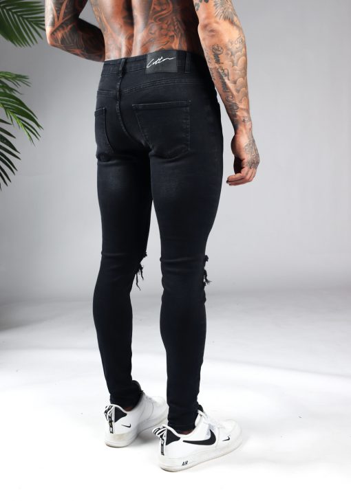 Achterkant zwarte heren skinny jeans met scheuren op de knieën. Gemaakt van super stretch stof en voorzien van vier broekzakken, knoopsluiting en riemlussen.