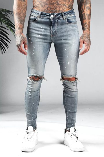Voorkant blauwe denim heren jeans met skinny pasvorm, gescheurde knieën en verfspetters.