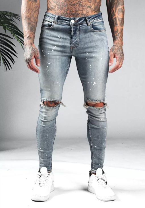 Voorkant blauwe denim heren jeans met skinny pasvorm, gescheurde knieën en verfspetters.