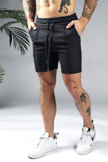 Vooraanzicht comfortabele heren chino shorts in zwarte kleur, met skinny fit en gemaakt van luxe stretch stof. Voorzien van twee broekzakken en rekbare taille met trekkoord. Gecombineerd met witte sneakers.