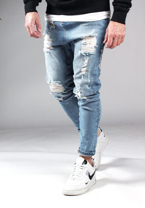 Linker zijaanzicht denim baggie damaged heren jeans met scheuren. Voorzien van vier zakken, knoopsluiting en riemlussen.