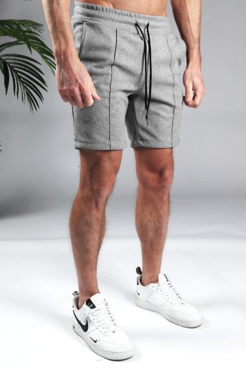Vooraanzicht comfortabele heren chino shorts in grijze kleur, met skinny fit en gemaakt van luxe stretch stof. Voorzien van twee broekzakken en rekbare taille met trekkoord. Gecombineerd met witte sneakers.