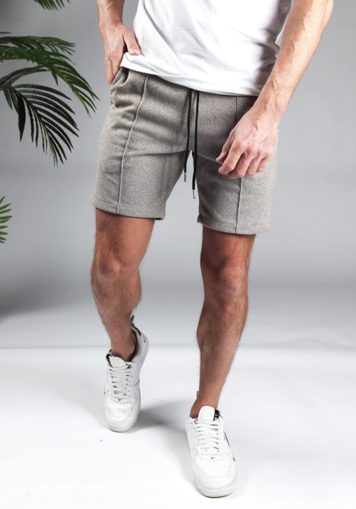 Vooraanzicht comfortabele heren chino shorts in zandkleur, met skinny fit en gemaakt van luxe stretch stof. Voorzien van twee broekzakken en rekbare taille met zwart trekkoord. Gecombineerd met witte sneakers en een wit T-shirt.
