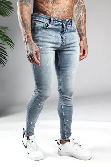 Rechter zijaanzicht licht blauwe denim heren skinny jeans met verfspetters. Voorzien van twee broekzakken, twee kontzakken, knoopsluiting en riemlussen.
