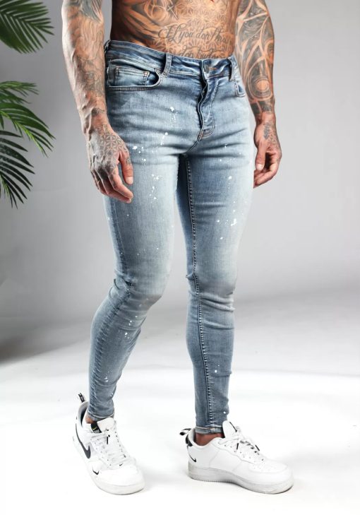 Rechter zijaanzicht licht blauwe denim heren skinny jeans met verfspetters. Voorzien van twee broekzakken, twee kontzakken, knoopsluiting en riemlussen.