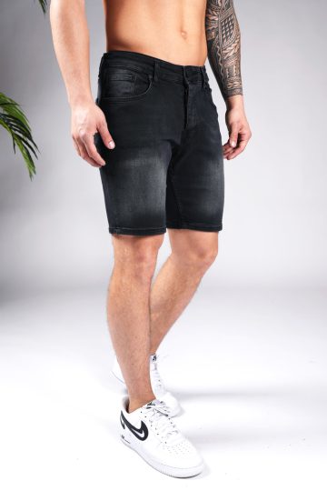 Schuin rechter vooraanzicht van het onderlichaam van een model gekleed in zwarte jean shorts gecombineerd met witte sneakers.