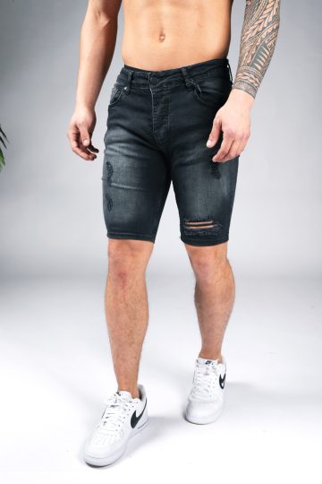Linker vooraanzicht van model gekleed in zwarte jean shorts met damaged details.