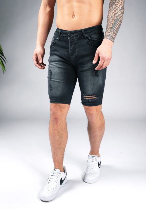 Linker vooraanzicht van model gekleed in zwarte jean shorts met damaged details.