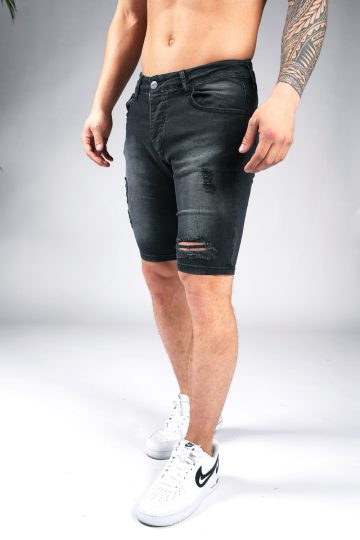 Linker schuin vooraanzicht van model gekleed in zwarte jean shorts met damaged details.