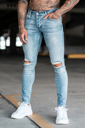 Voorkant lichte denim heren skinny jeans met gescheurde knieën, gemaakt van stretch stof. Voorzien van twee zakken aan de voorzijde, twee kontzakken, knoopsluiting en riemlussen.