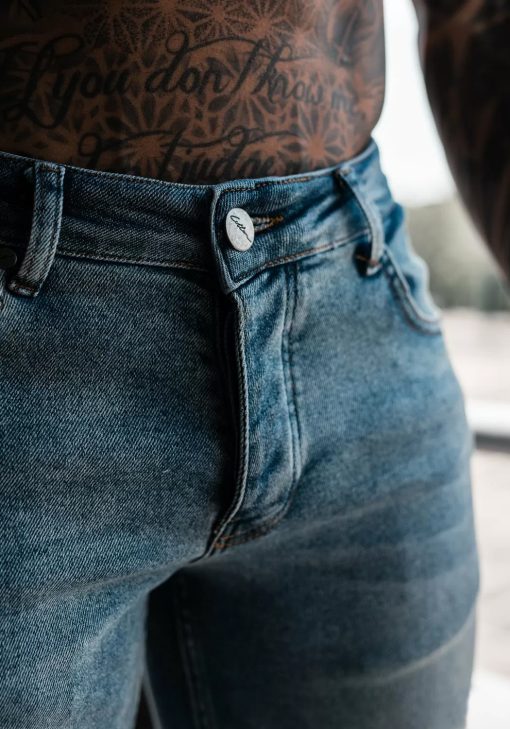 Close up knoopsluiting lichte denim heren skinny jeans met gescheurde knieën, gemaakt van stretch stof.
