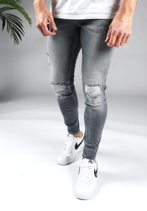 Voorkant grijze damaged denim heren skinny jeans met scheuren en verfspetters.