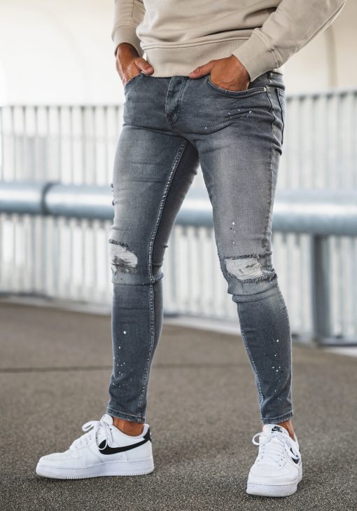 Linker zijkant grijze damaged denim heren skinny jeans met scheuren en verfspetters.