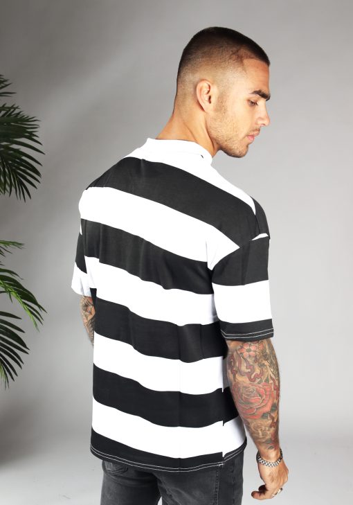 Achteraanzicht van model gekleed in zwart wit gestreepte t-shirt. De strepen zijn dik en lopen horizontaal.