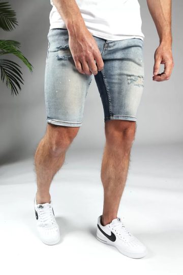 Schuin linker vooraanzicht van model gekleed in lichtblauwe trench jean shorts. De shorts hebben damaged details en een skinny fit.