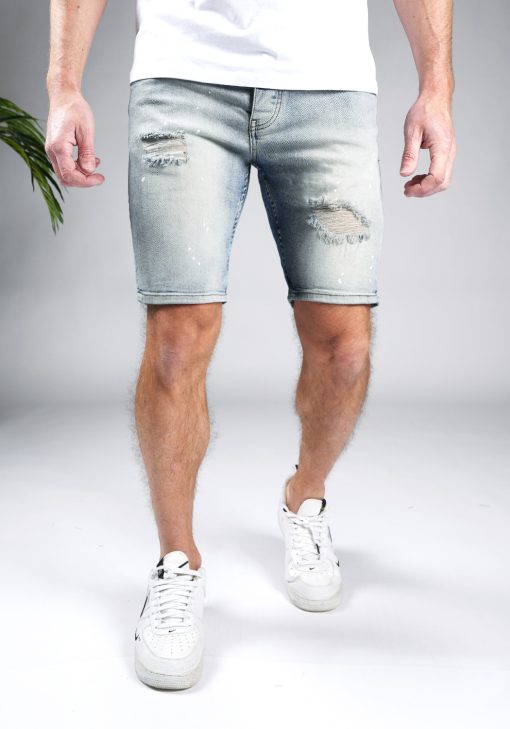 Vooraanzicht van model gekleed in lichtblauwe trench jean shorts. De shorts hebben damaged details en een skinny fit.