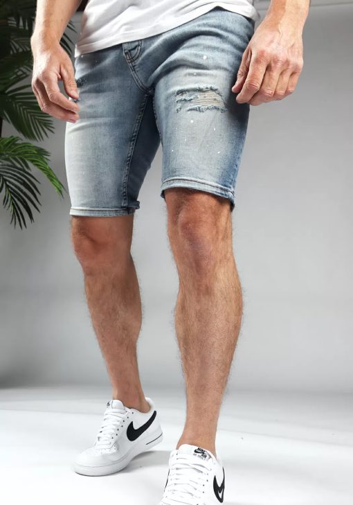 Schuin linker vooraanzicht van model gekleed in lichtblauwe trench jean shorts. De shorts hebben damaged details en een skinny fit.
