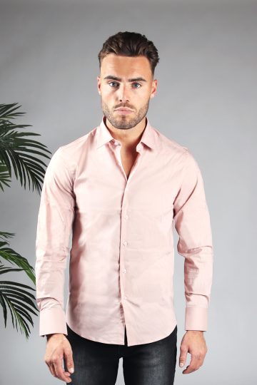 Vooraanzicht van heren overhemd in een roze kleur, met roze knoopjes en een slimfit pasvorm. Het model draagt een donkere jeans en heeft zijn armen langs zijn lichaam.