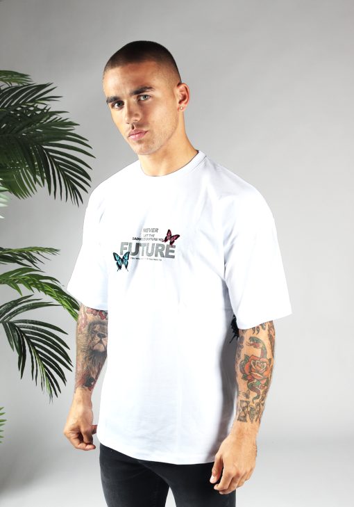 Vooraanzicht van heren T-shirt in witte kleur, met ronde hals en een oversized pasvorm. Het T-shirt is voorzien van vlinder print in roze en blauwe kleur en tekst op de borst. Het model draagt een donkere jeans en heeft armen langs zijn lichaam.
