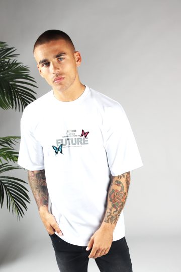 Vooraanzicht van heren T-shirt in witte kleur, met ronde hals en een oversized pasvorm. Het T-shirt is voorzien van vlinder print in roze en blauwe kleur en tekst op de borst. Het model draagt een donkere jeans en heeft zijn rechterhand in zijn rechterbroekzak.