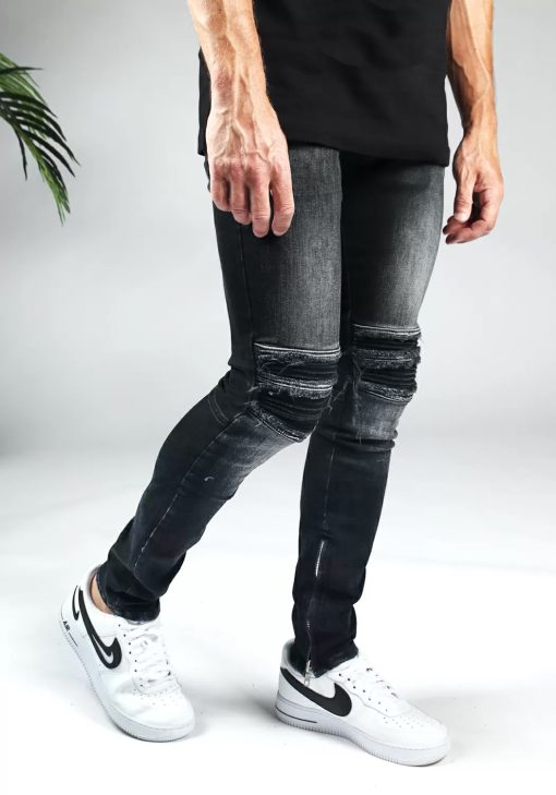 Rechter zijaanzicht zwarte heren jeans slim fit model met scheuren bij de knieën en een rits aan de binnenkant van de enkel.