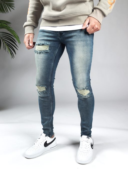 Linker zijkant blauwe heren skinny jeans met scheuren in de broekspijpen en gemaakt van stretch stof. Voorzien van vier zakken, knoopsluiting en riemlussen.