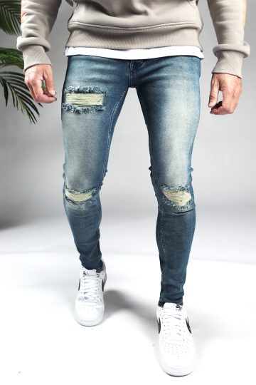 Voorkant blauwe heren skinny jeans met scheuren in de broekspijpen en gemaakt van stretch stof. Voorzien van vier zakken, knoopsluiting en riemlussen.