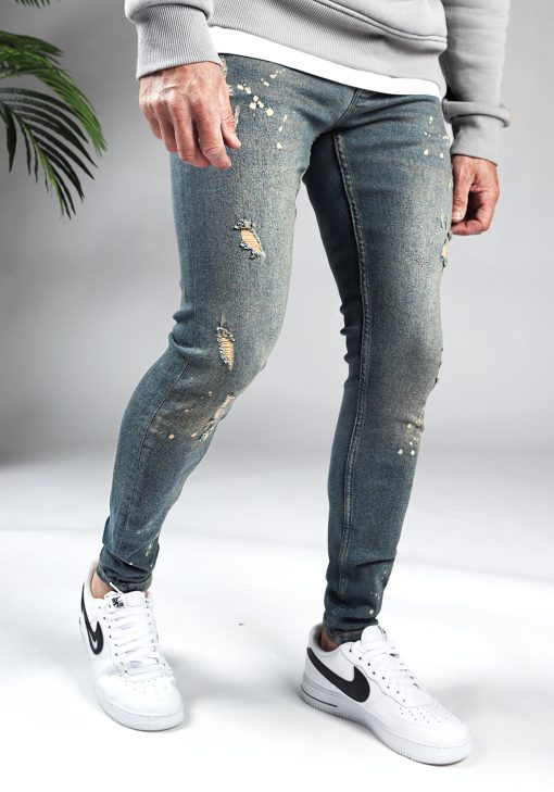 Rechter zijaanzicht damaged heren skinny jeans met zandkleurige details. Voorzien van vier zakken, knoopsluiting en riemlussen.